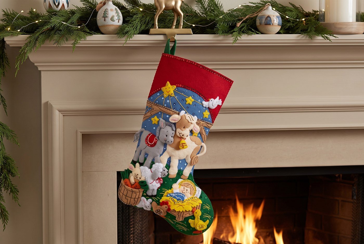 Bucilla Christmas Nativity felt-applique stocking 89531E — deep blue star-scattered base with stable animals and baby Jesus in a golden manger, embellished with sequins and beads